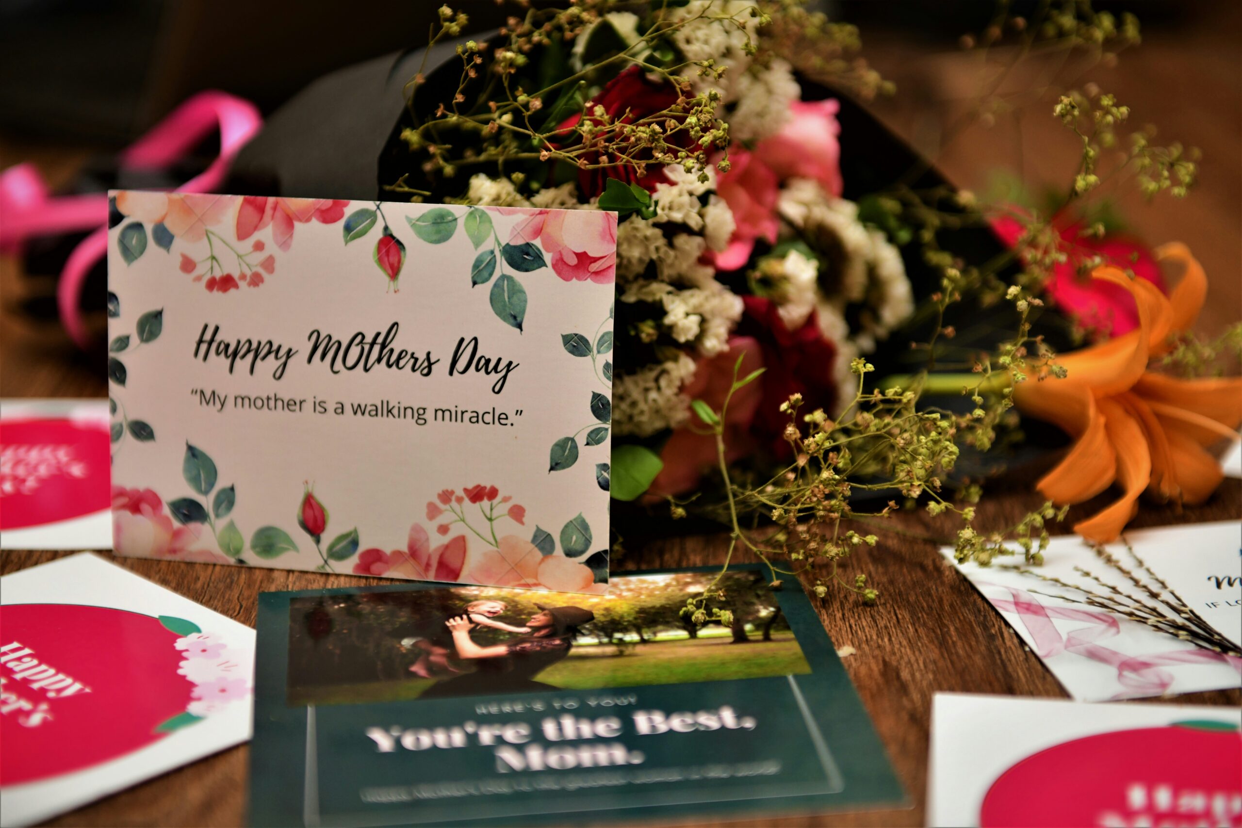 Carte de fête des mères avec message touchant, entourée de fleurs et de bouquets sur une table en bois